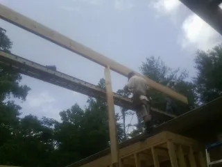 Carpenter setting a ridge beam over a new addition frame — Ice Dam Removal by Roofing Brothers in Peachland