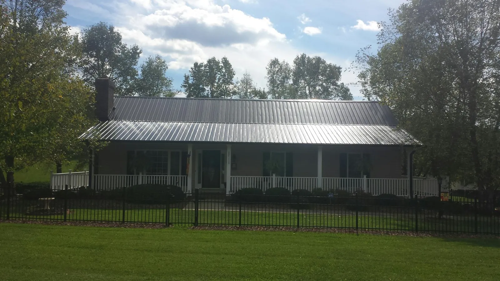Gray metal roof on a brick ranch with a full width front porch — Gutter Guard Installation work by our crew in Peachland