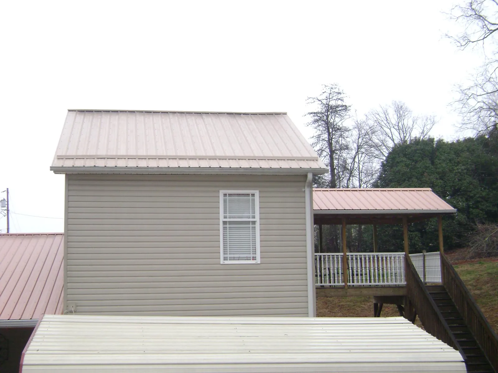 Tan metal roofs on a two story addition and attached porch, from a Roof Replacement job in Peachland