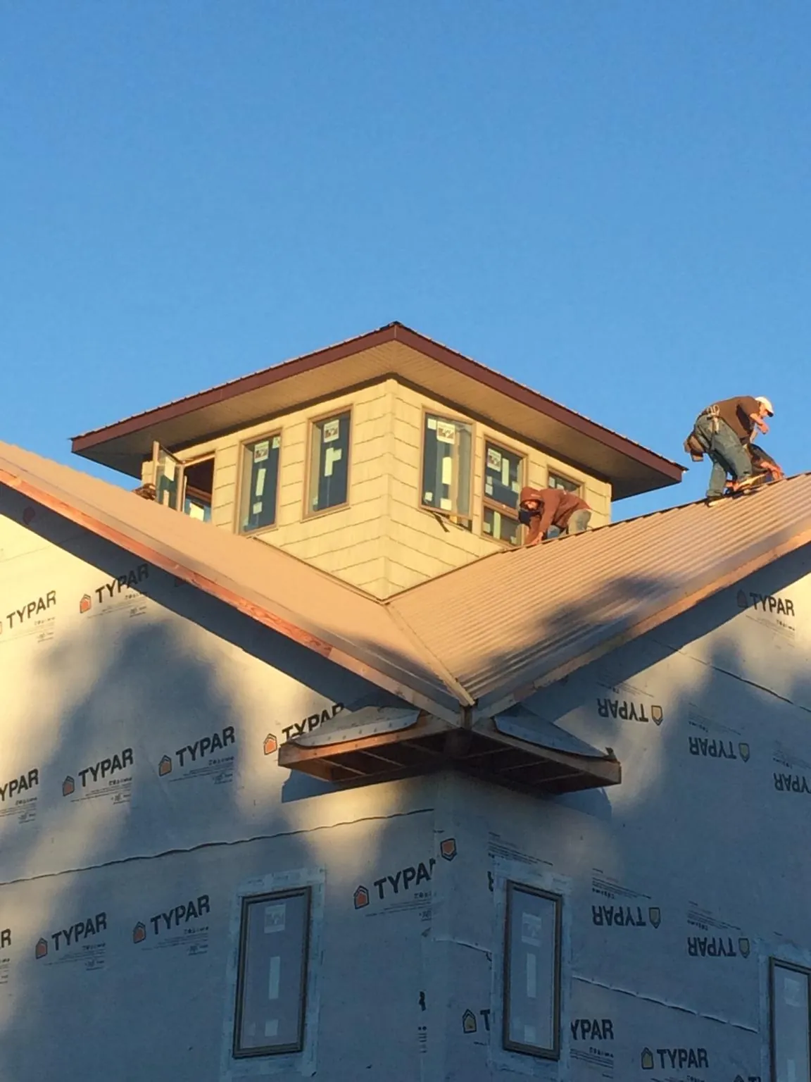 Roofers working around a rooftop cupola on a new metal roof at sunset — Roof Waterproofing in Peachland by Roofing Brothers
